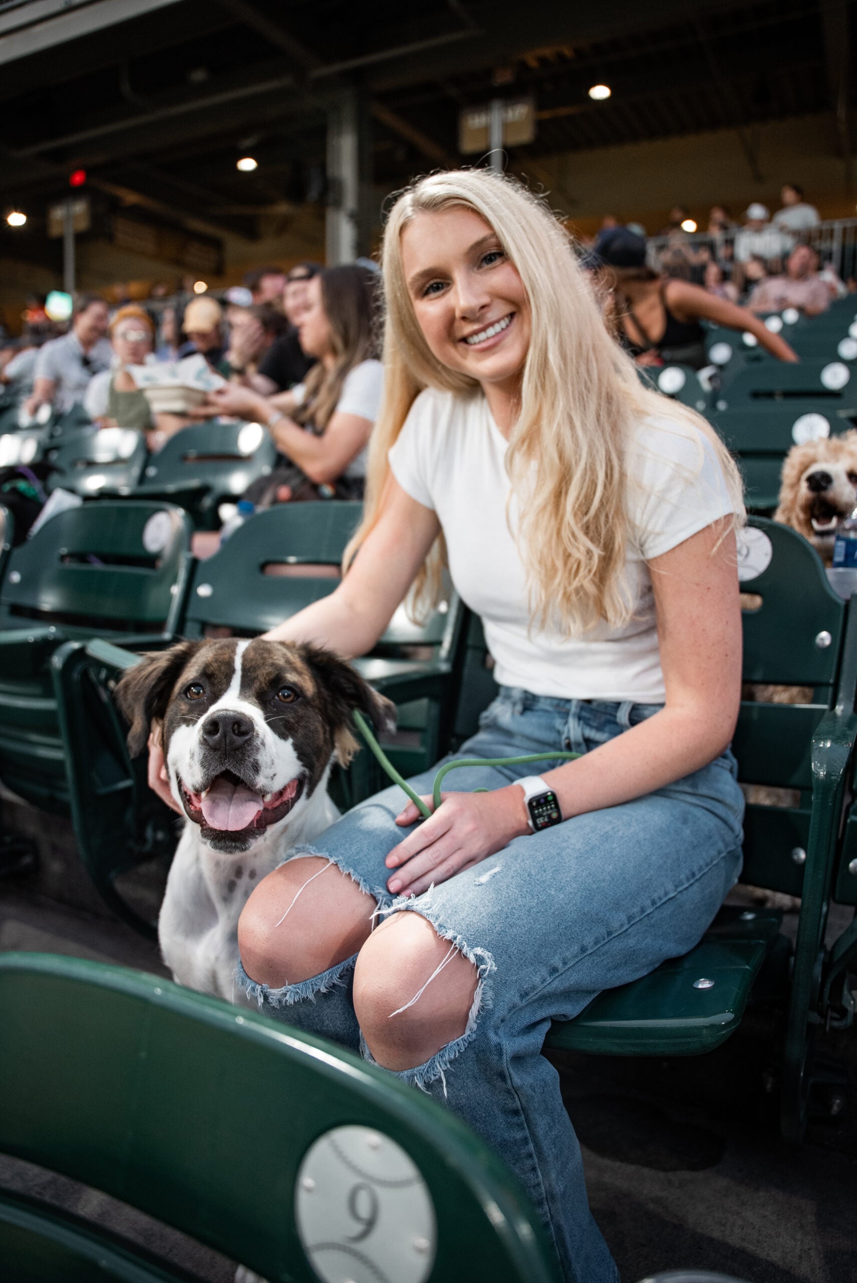 Smiling Obedient K9 client with her dog in the stands at Truist Field during Bark in the Ballpark