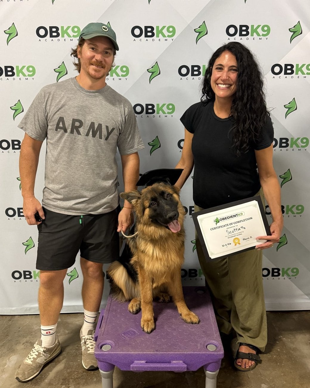 Scottie, a German Shepherd puppy, in her graduation cap with her owners and certificate at Obedient K9 Academy in Charlotte